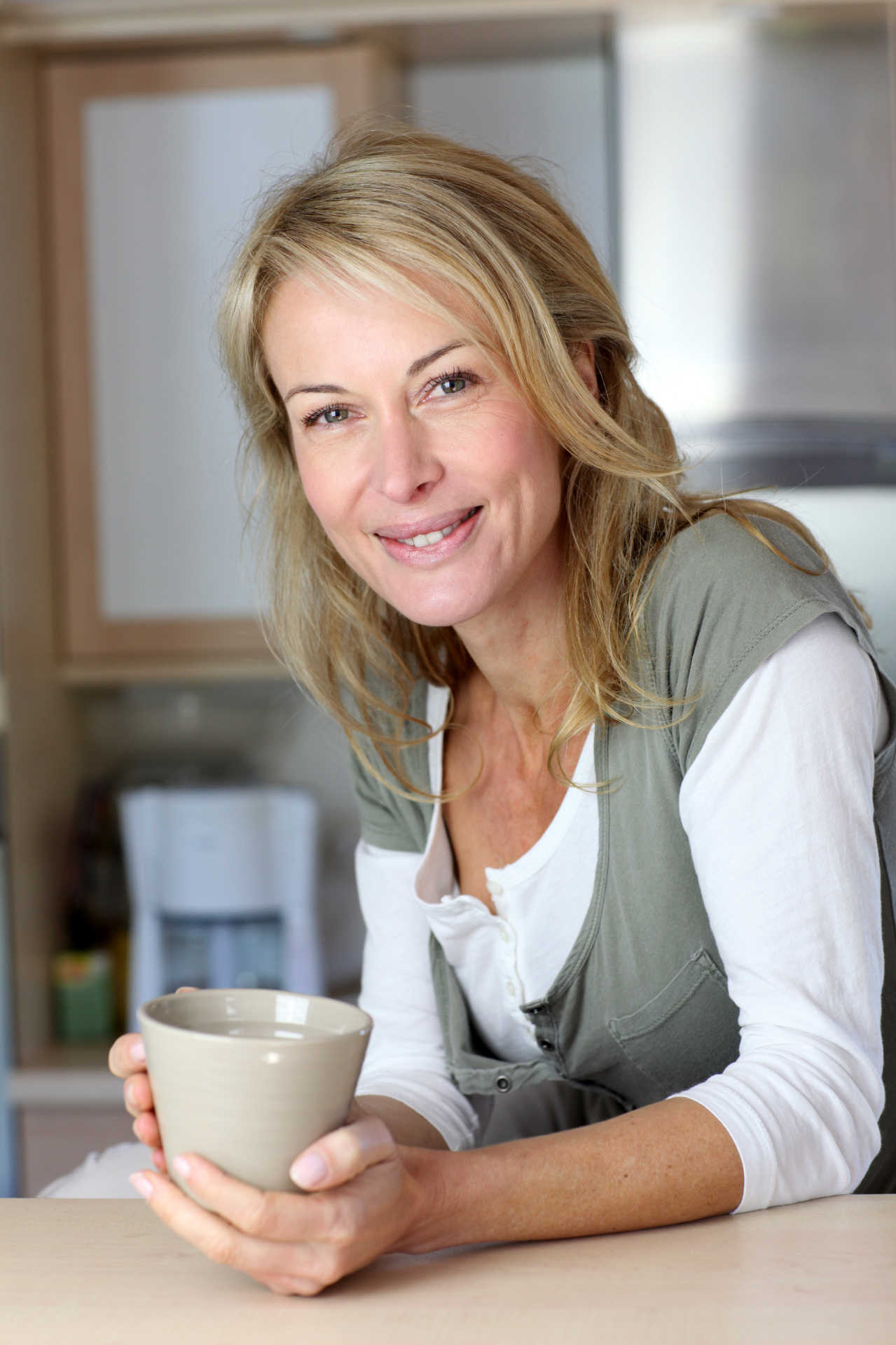 Femme rayonnante dans sa cuisine, tasse à la main